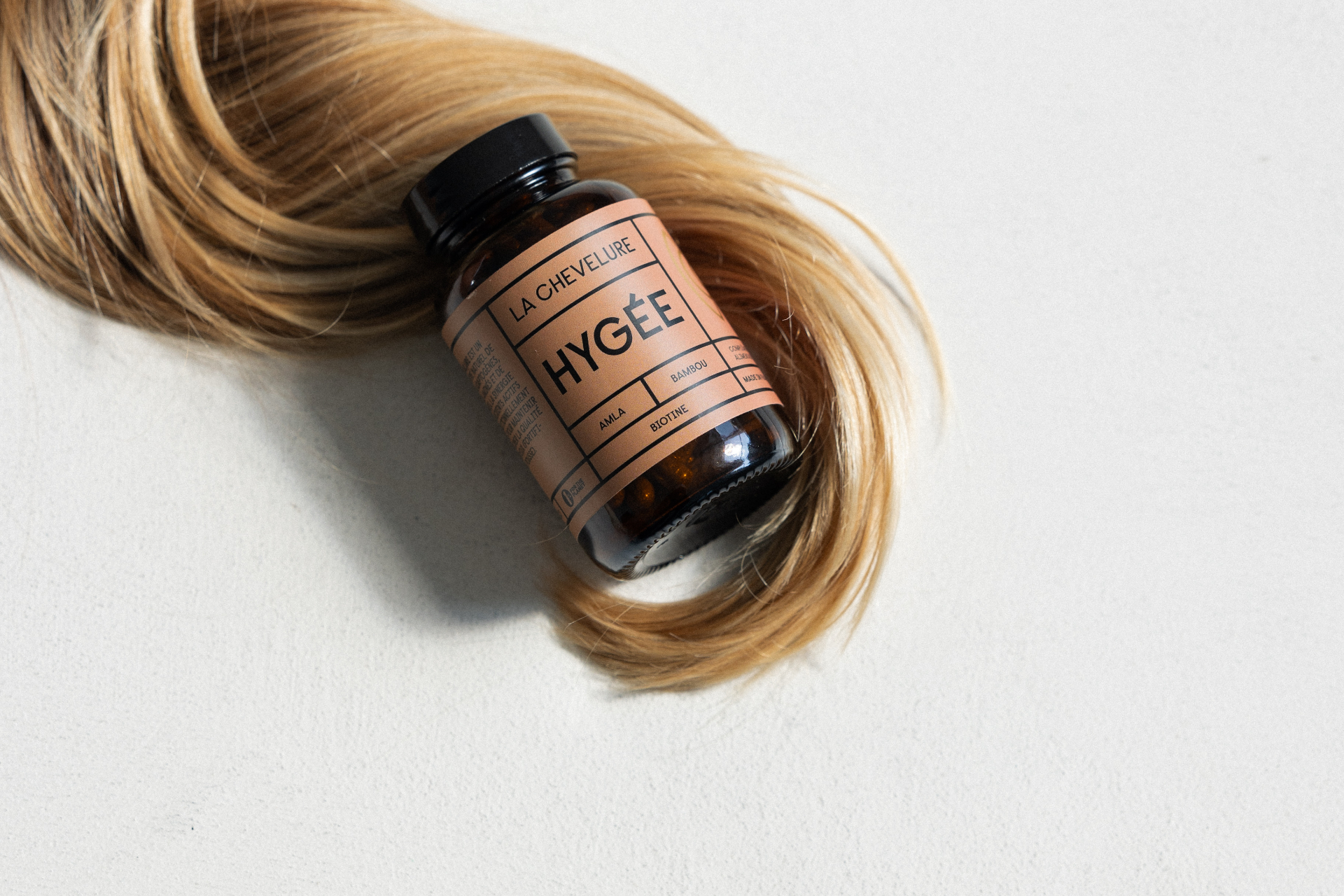 Hygée — complément alimentaire La Chevelure posé sur une mèche de cheveux